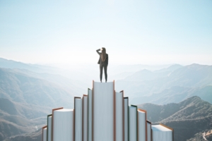 Back,View,Of,Businesswoman,Standing,On,Book,Mountain,On,Sky